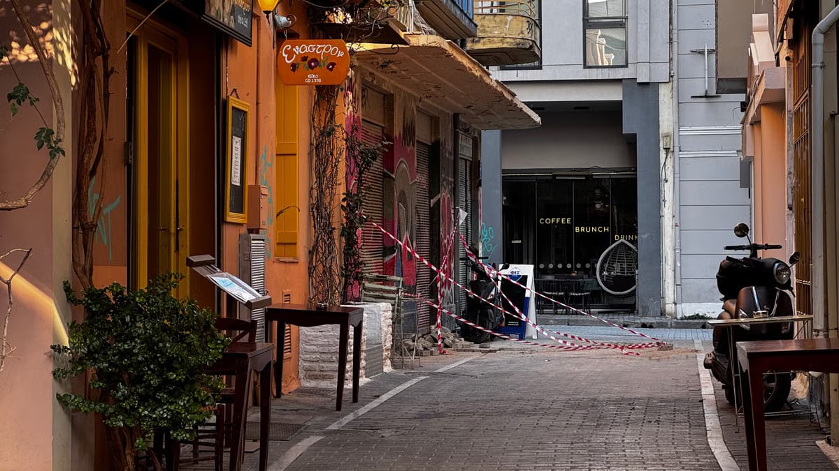 Explore a quaint alleyway in Athens, Greece, featuring inviting cafés and warm colors on a sunny day.